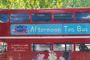 Red Double Decker Bus with "Afternoon Tea Bus Tour" Banner and Peppa Pig Logo